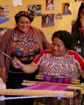 Guatemalan women hand weaving on a loom.
