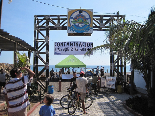 People gathering around the entrance to a beach with banners hung touting conservation.
