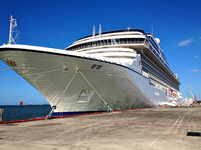 View from the dock looking up at the prow of a mid-sized cruise ship.