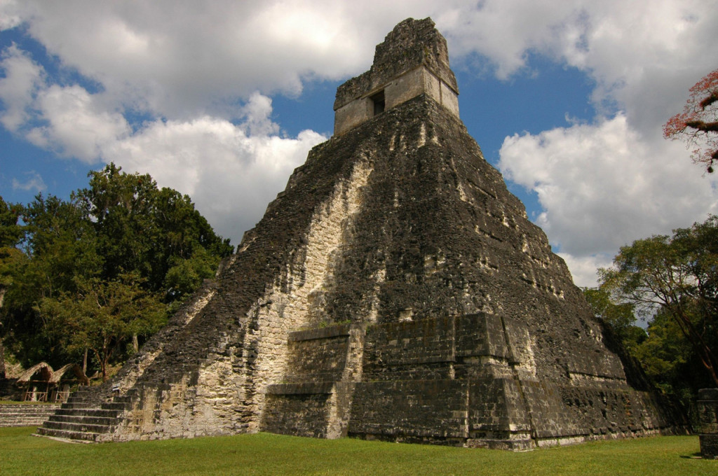 Pyramidal temple with pale stones showing through moss.