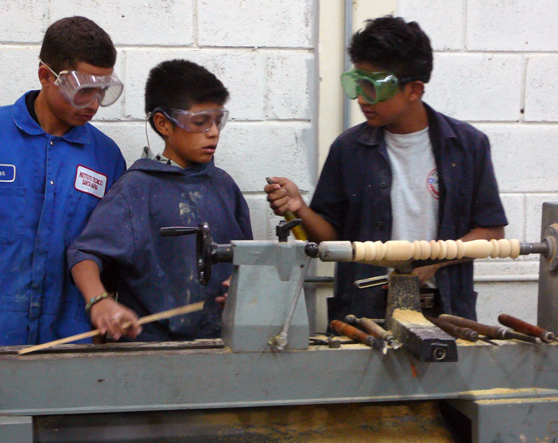 Boys in a shop class run by El Hogar learning to use a lathe.