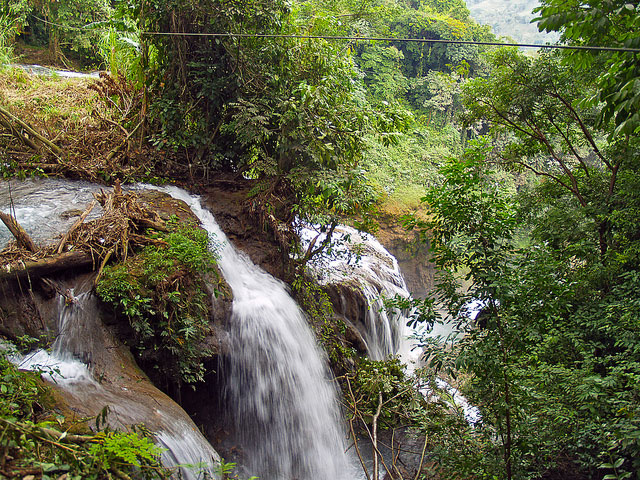 A zipline crosses over the edge of a rushing waterfall.