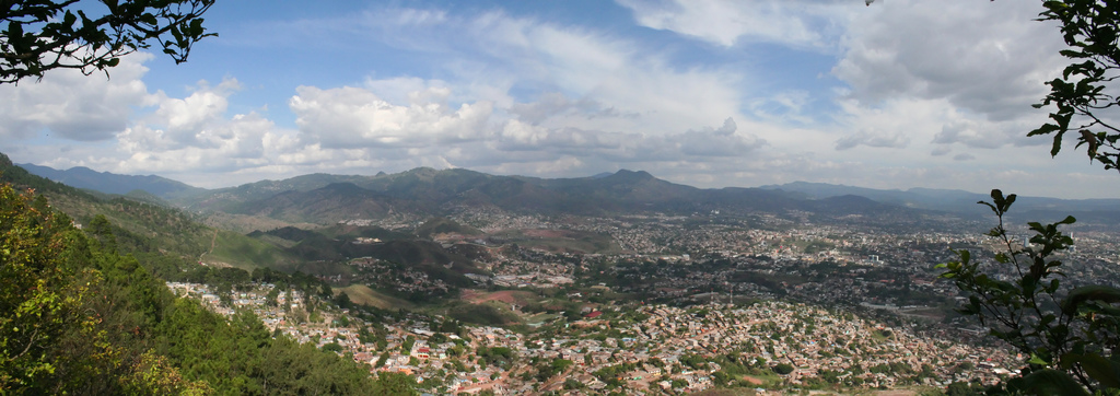Hill-top panorama of the city of Tegucigalpa with large cumulous clouds in a bright blue sky.