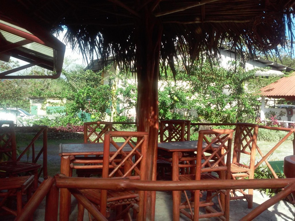 Wooden patio furtniture in the shade at the APROVACA hostel grounds.