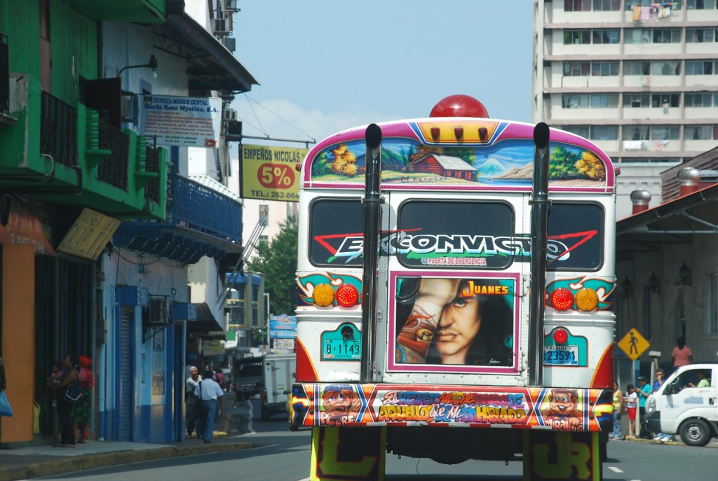 Motorist's view of the back of a city bus with colorful advertisements.