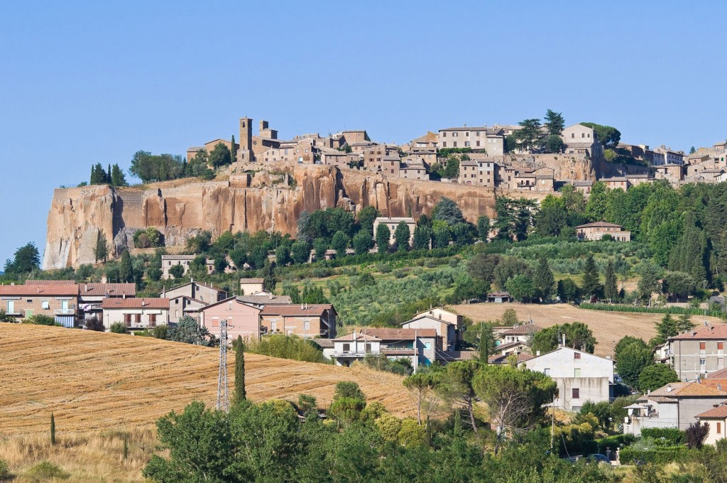 A panoramic view of a countryside town with homes clustered amongst rolling mediterranean hills.