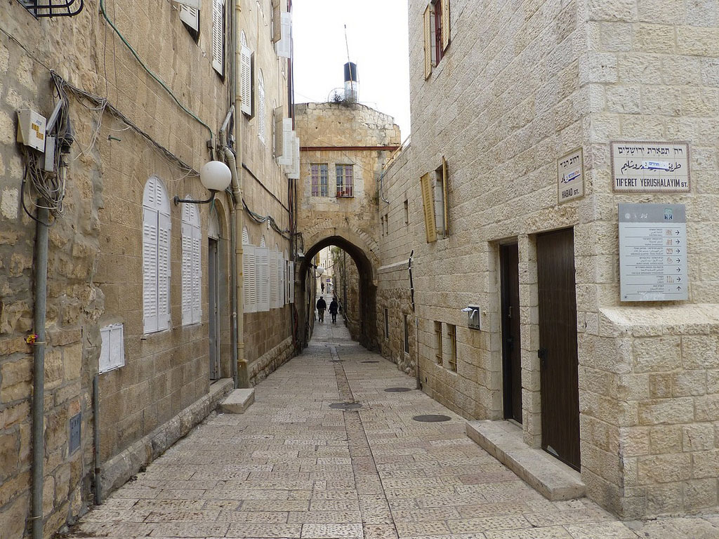 White-shuttered windows line a stone-paved street in the Jewish Quarter.
