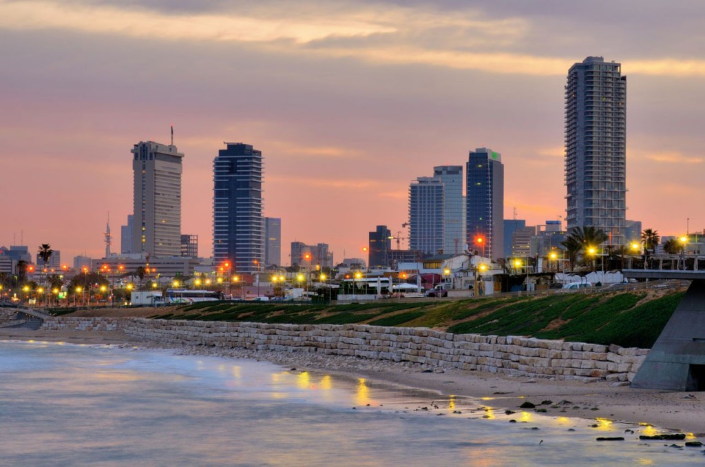 View of the Tel Aviv skyline at dusk with lights reflecting into the water of the Mediterranean.