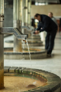 Water spills from a spigot into a shallow fountain in Karlovy Vary.