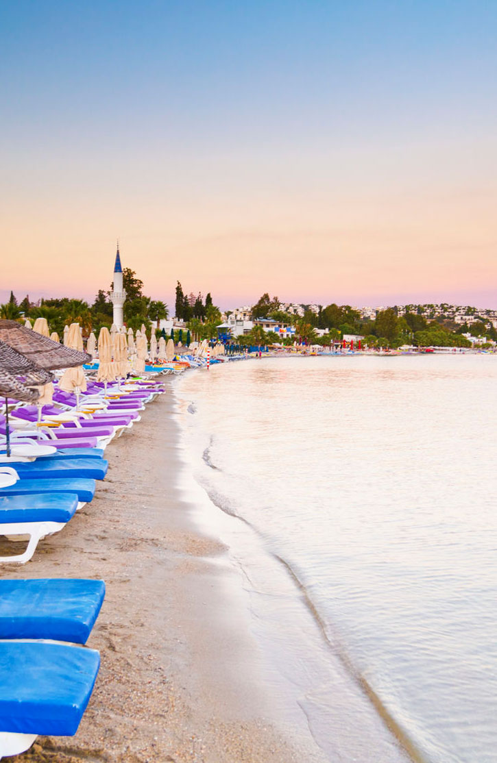 Chaise lounges lining the waterfront at Bitez beach in Turkey.