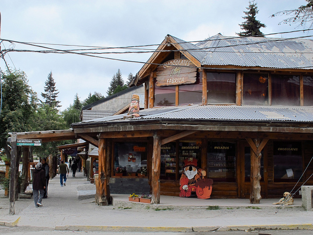 An alpine building with cafe seating on a second-floor patio and a chocolatier on the ground floor.