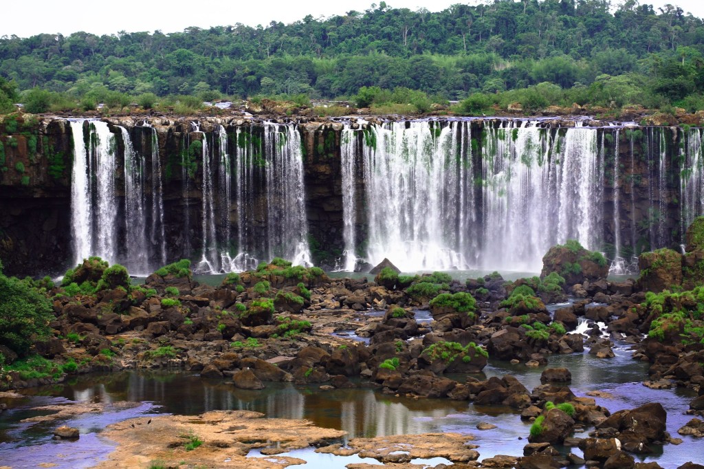 A long curtain of water spills over verdant cliffs.