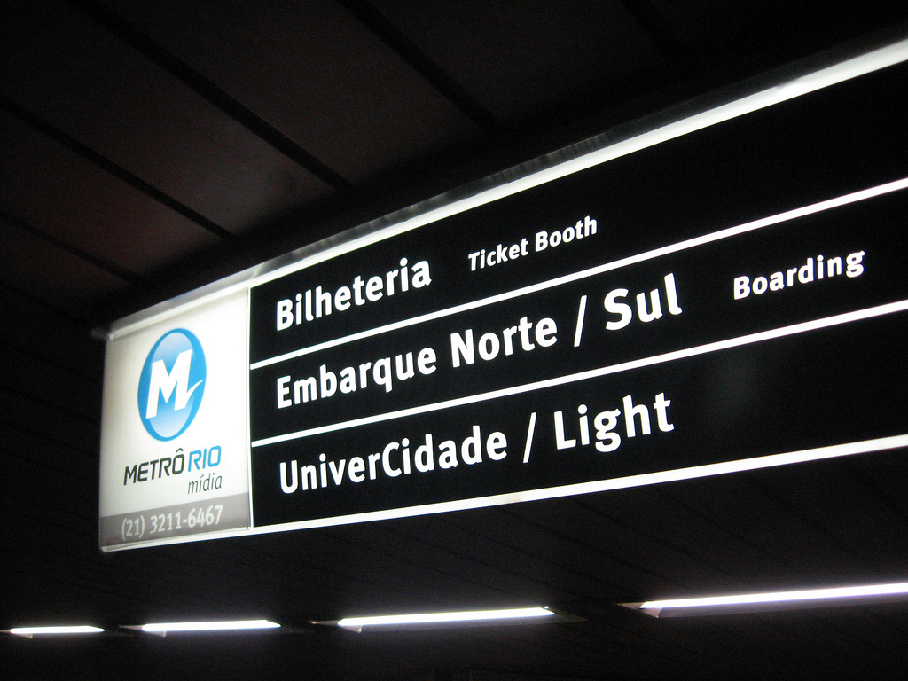 A glowing sign with the Metro logo and station stops shines white on black.