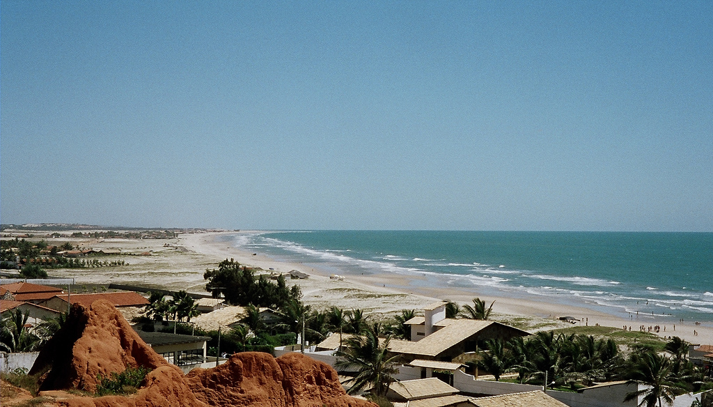 View of coastal Fortaleza, with a long strip of beach visible and a cluster of homes.