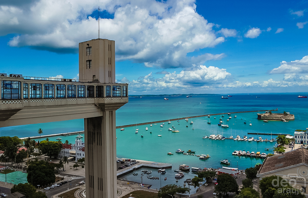 A windowed footbridge leads to a tall, rectangular structure with an impressive view of the bay stretching out to the horizon.