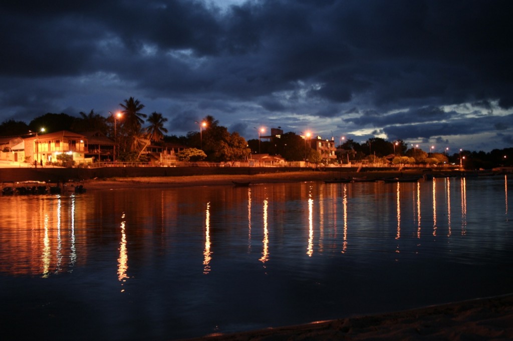 Warm lights reflect in the water as the evening sky peeks through heavy clouds.