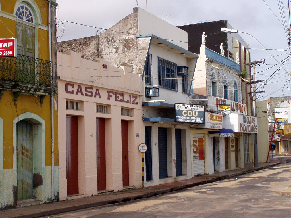 View down a street in Santarém lined with businesses, one of which has Casa Feliz painted along the front.