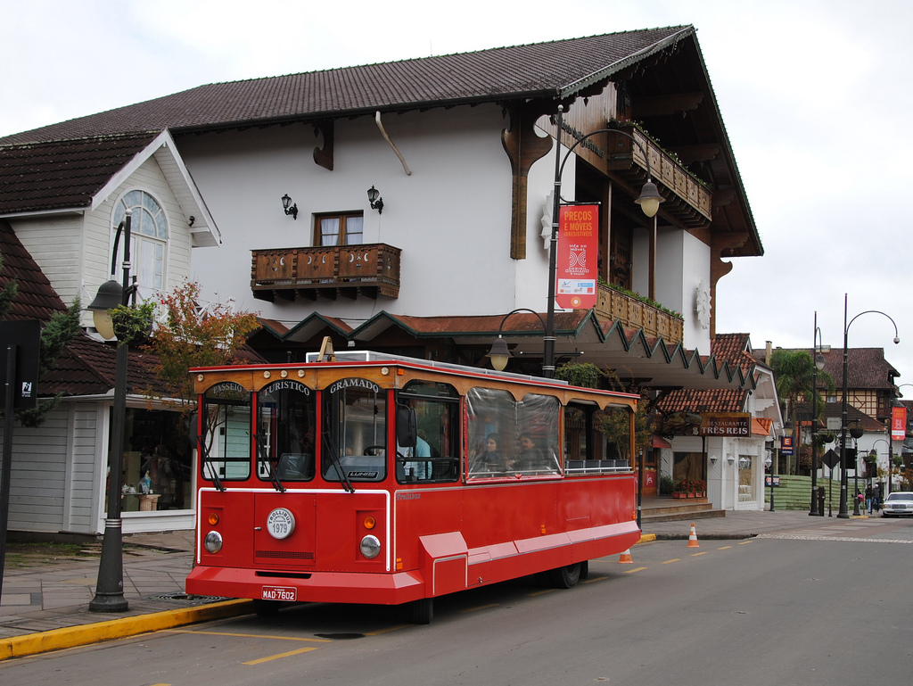 A red tourbus waits in front of buildings on a charming street lined with chalets.