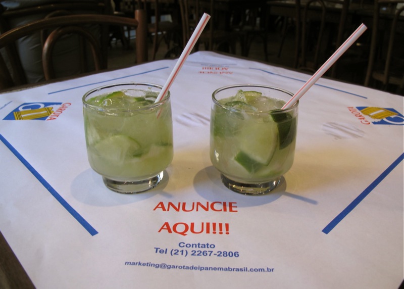 Two cocktails filled with lime wedges on a napkin from Garota de Ipanema bar.