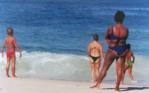People in bikinis facing the ocean