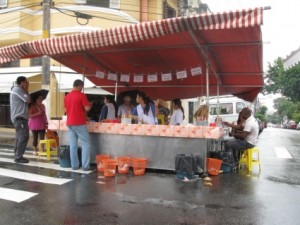 Man buying pasteis at a stand in the rain