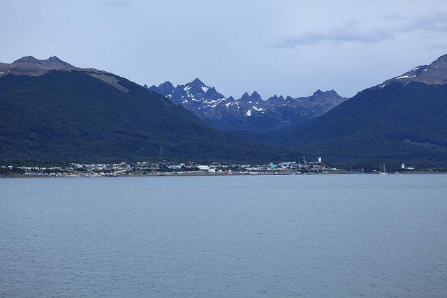 View of the coastal town of Puerto Williams nestled at the base of steep mountains.