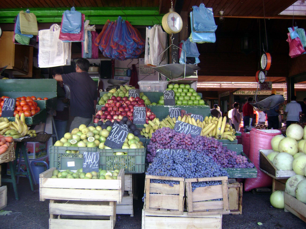 A market stall with crates overflowing with grapes, bananas, and other produce.