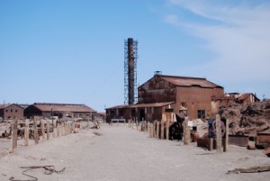 Piles of rusted metal and a warehouse-style building red with rust.