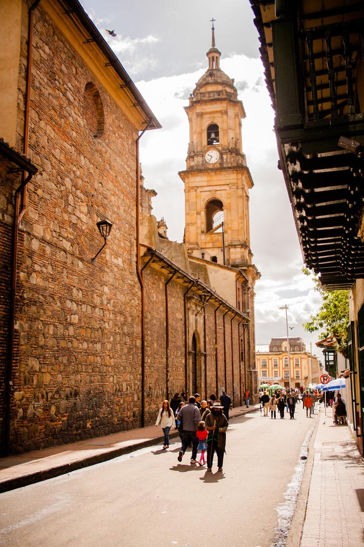 People walking alongside the Catedral Primada towards Plaza de Bolívar.