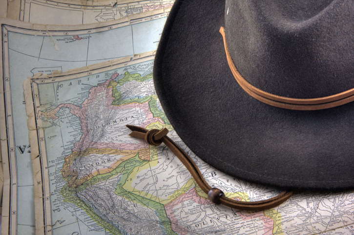 A felt hat rests on a vintage map of South America.