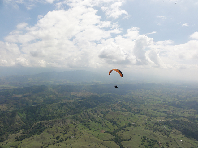 Aerial view of a paraglider high above the hilly landscape of Roldanillo, Colombia.