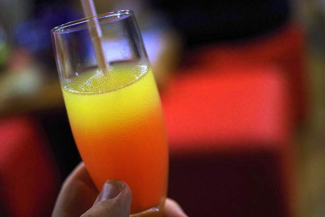 Photo of a glass with a yellow and orange tropical drink.