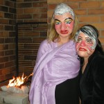 Amy and a friend wear painted masks with exaggerated features.