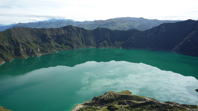 Luminous green water fills the caldera of an extinct volcano.