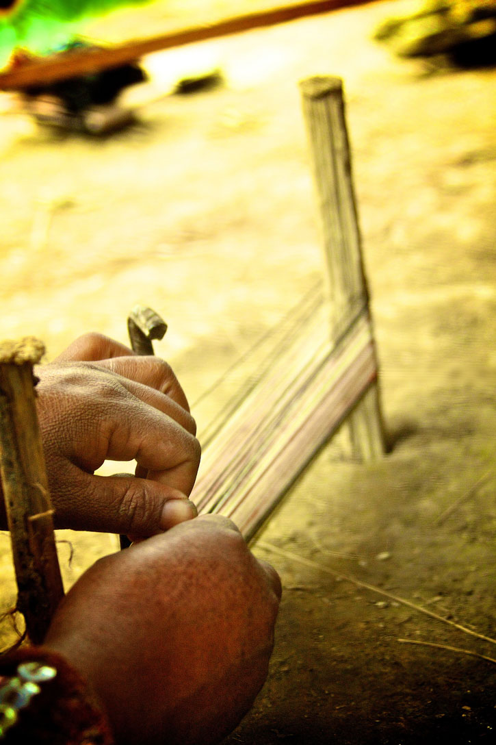 View of a weaver's hands looping thread around a loom at Awamaki in Ollantaytambo, Peru.