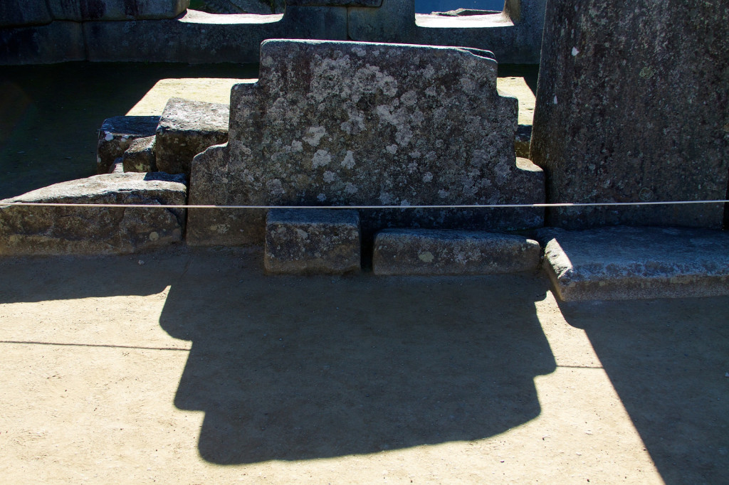 A stone carved into the stepped pattern of the upper half of an incan cross combines with its shadow to create a full cross.