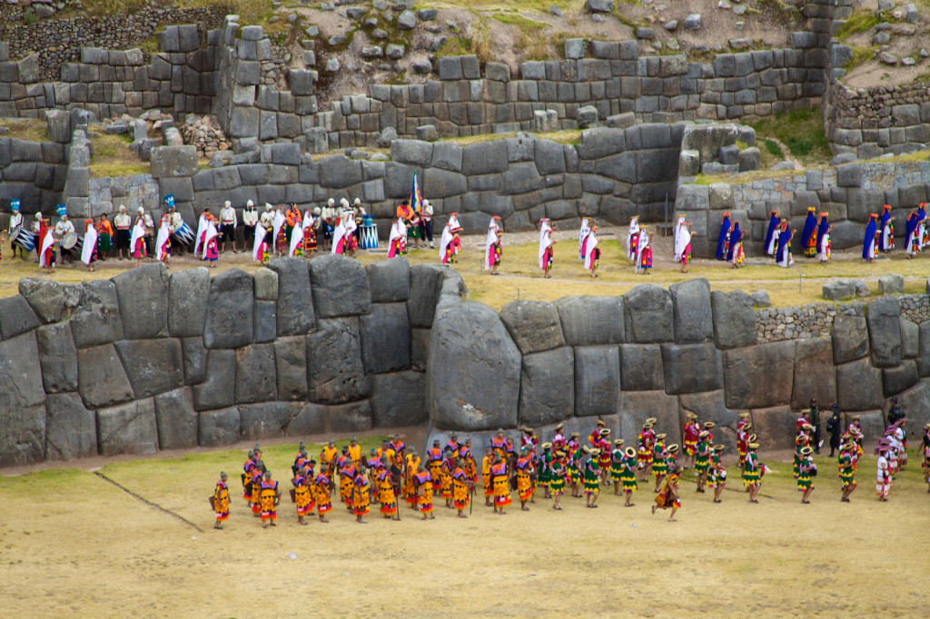 Dancers and drummers in colorful garb celebrate the solstice, lining up along the grassy stone terraces.