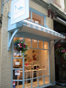 View of the window display and overhang of a cute boutique shoe shop with white and powder blue trim.
