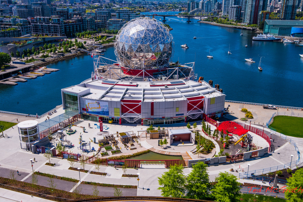 Aerial view of the Science World building topped with a faceted glass sphere and colorful outdoor exhibits visible.