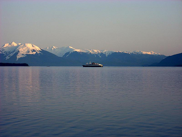 A photo of an Alaskan ferry boat against a vast mountain range.