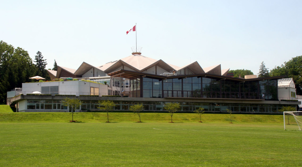 View across a wide green lawn of the Festival Theatre with modern angles and tall glass windows.