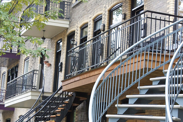 Front of a brick building with a tangle of spiral stairs out front.