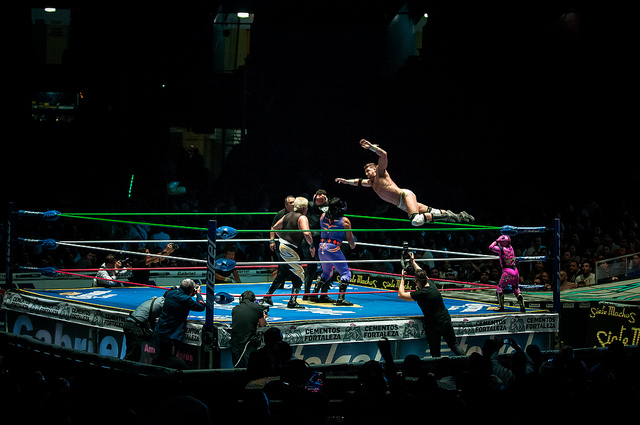 A Mexican wrestler taking a flying leap into the center of the ring at Arena México.