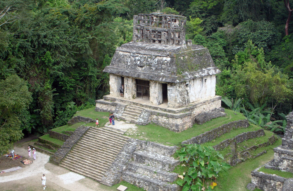 View of a maya temple surrounded by grassy terraces.