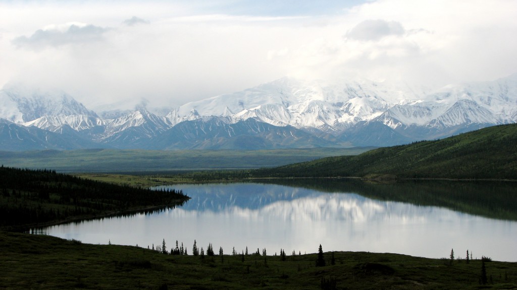 Snow-capped mountains of Denali National Park are reflected in the mirror-like water of Wonder Lake.
