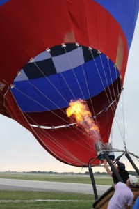 A gout of flame ignites as a hot air balloon is being filled.