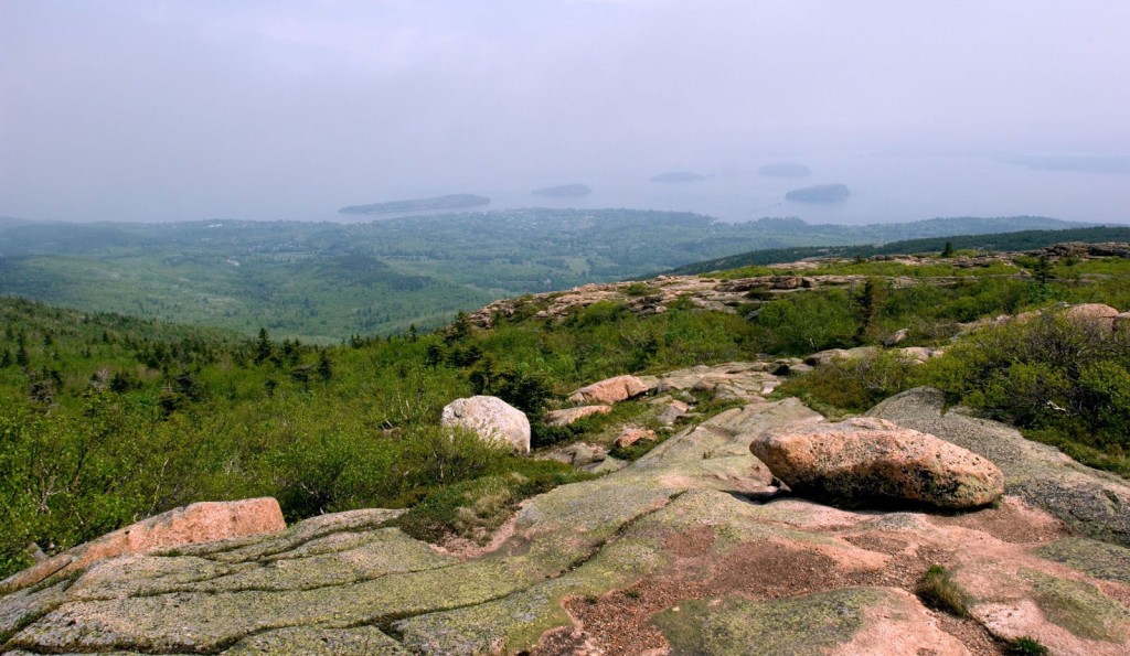 A plateau of smooth mossy stones offers a dramatic view of Maine greenery and the ocean dotted with small islands.