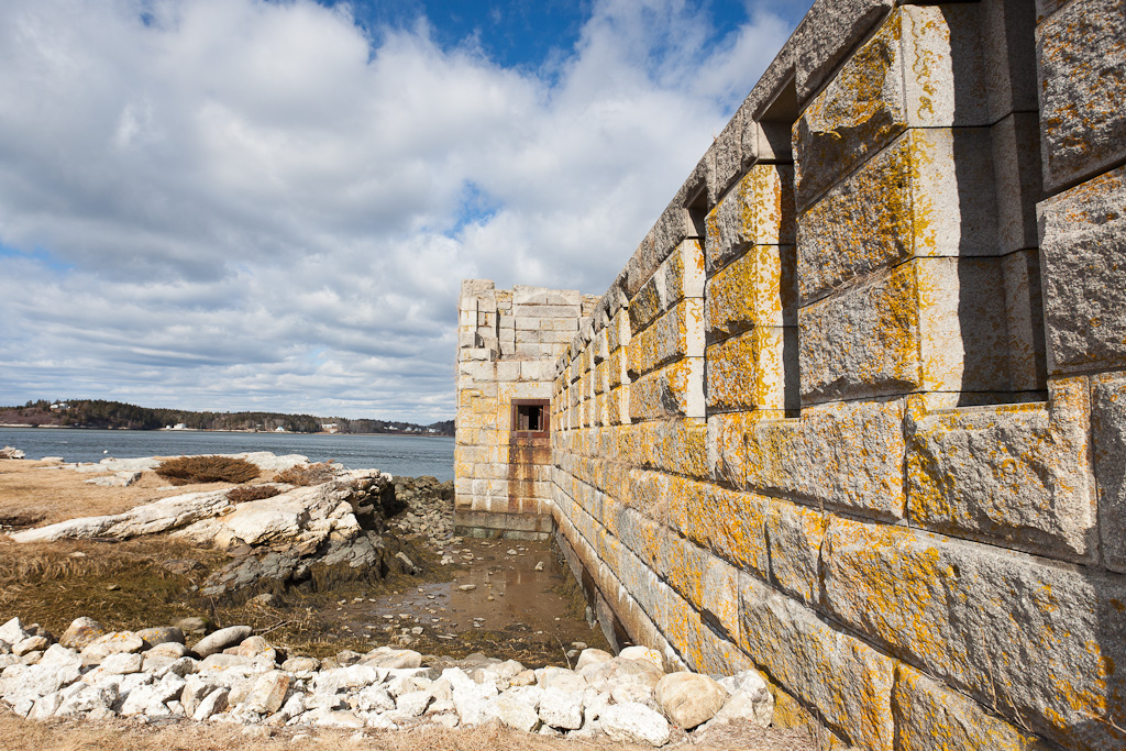 The stone wall of the fort stretches towards the camera while the ocean is visible beyond the structure.
