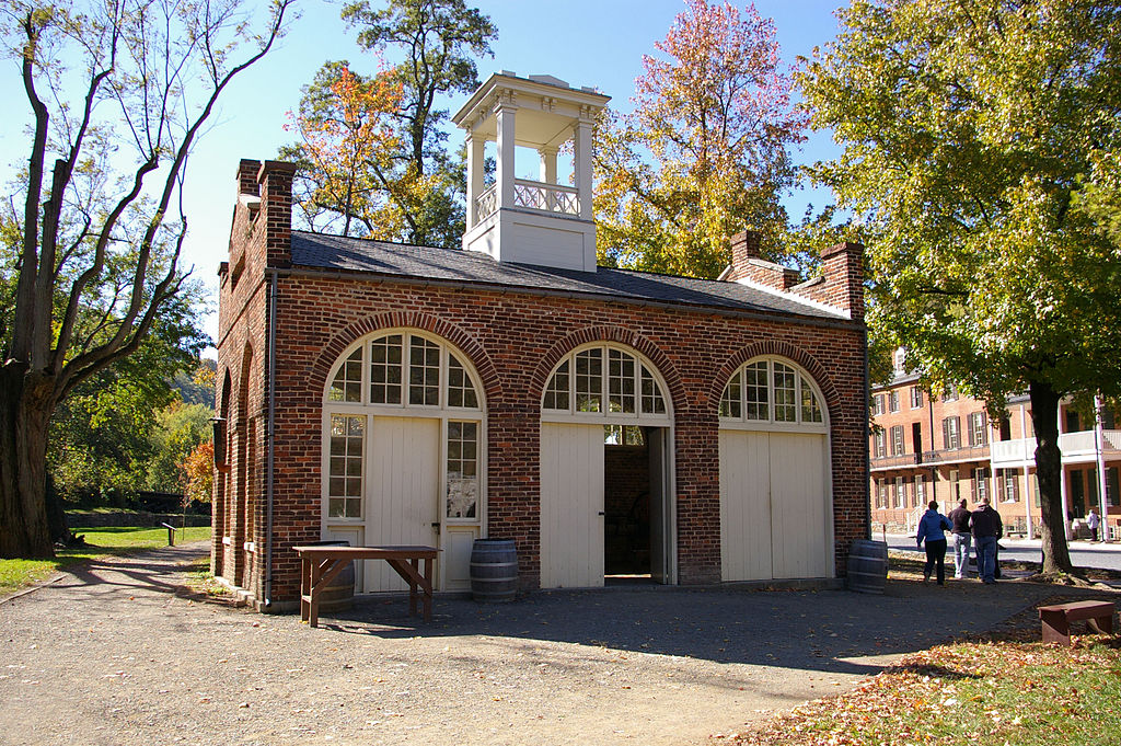 A one story brick guard house with high arches featuring double doors and paned windows.