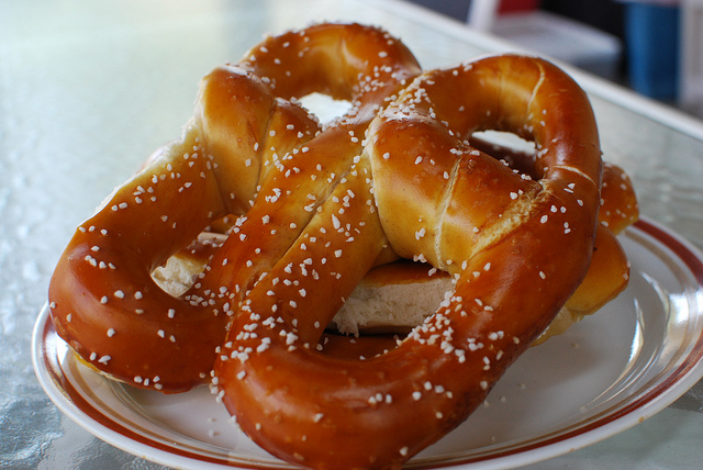 A golden brown soft-pretzel covered in big pieces of rock salt.